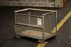 Leerer Gitterbox-Container auf einer Palette in einem industriellen Lagerbereich.