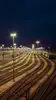 Beleuchteter Rangierbahnhof mit mehreren Gleisen und Güterwaggons bei Nacht