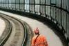 Bahnmitarbeiter in Schutzkleidung geht neben einem langen Güterzug auf einer Kurve