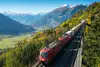 ÖBB-Güterzug mit Containern fährt durch eine Alpenlandschaft auf einer Hochbahnstrecke