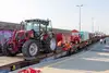 Landmaschinen werden von Mitarbeitenden auf Flachwagen eines Güterzugs verladen