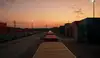 Containerterminal bei Sonnenuntergang mit gestapelten Containern und Güterzug auf Gleisen
