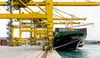 Frachtschiff am Containerterminal mit großen Kränen und gestapelten Containern am Hafen