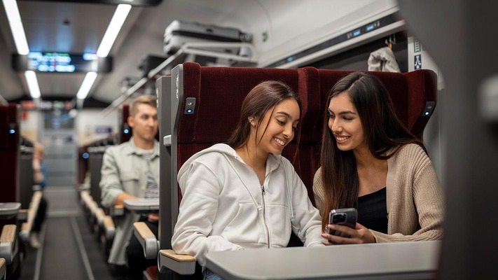 Ragazze nel vagone con i posti a sedere comfort guardano lo smartphone