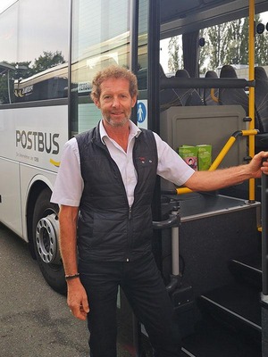 Postbus-Lenker steht vor seinem Postbus