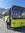 Postbus Lenker steht neben seinem Bus vor schönem Bergpanorama