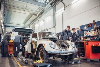 Lehrlinge beim Restaurieren eines Porsche