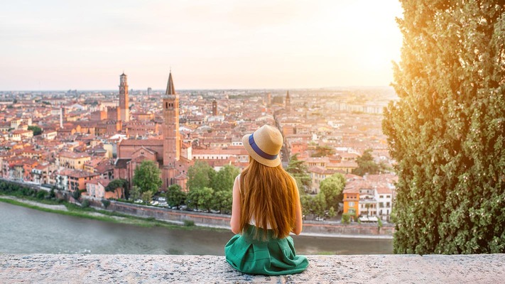 Eine junge Frau blickt von einem Hügel auf Verona