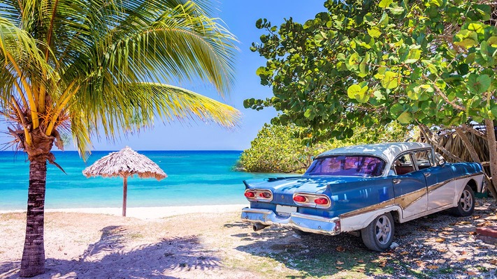 Ein typisch kubanisches Auto steht am Sandstrand