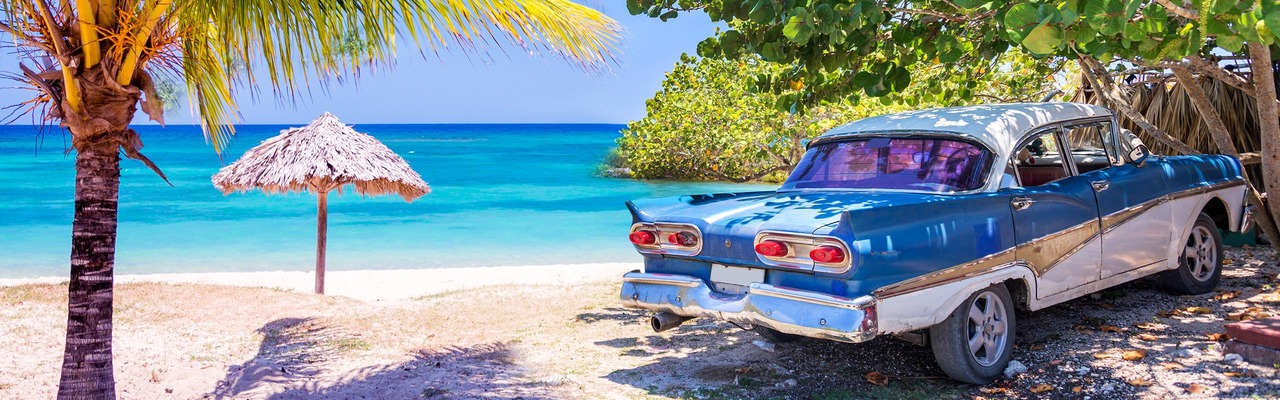 Ein typisch kubanisches Auto steht am Sandstrand