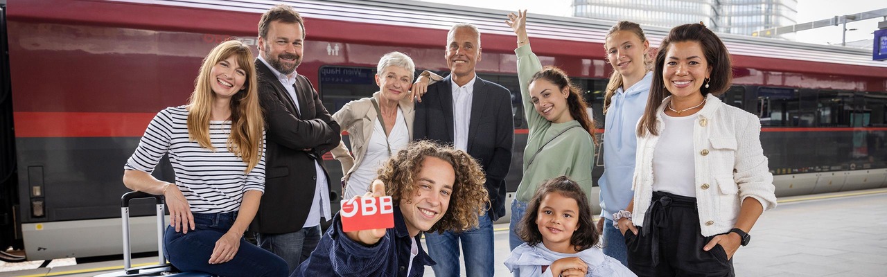 Reisende aller Altersklassen vor Zug zeigen ÖBB Vorteilscard