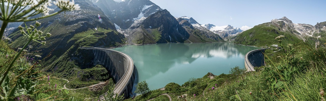 Hikers in front of the high mountain reservoir in Kaprun