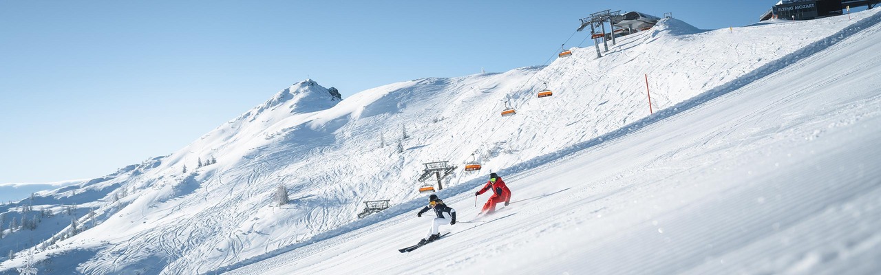 Skifahrer auf Piste vor Bergpanorama