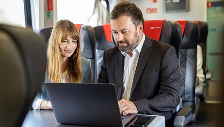 Mann und Frau in Business-Abteil schauen auf Laptop
