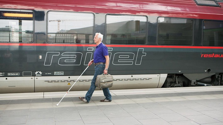 Sehbehinderter Fahrgast am Bahnsteig mit Blindenstock
