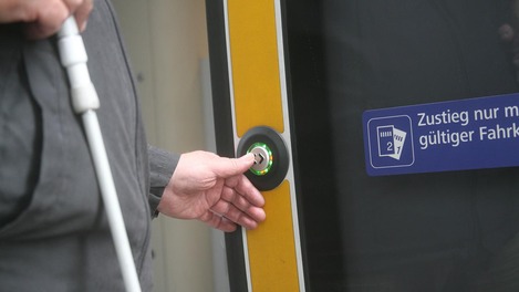 Fahrgast drückt Knopf bei barrierefreiem Einstieg